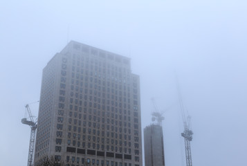 Southbank place tower block with construction cranes in fog, Lon