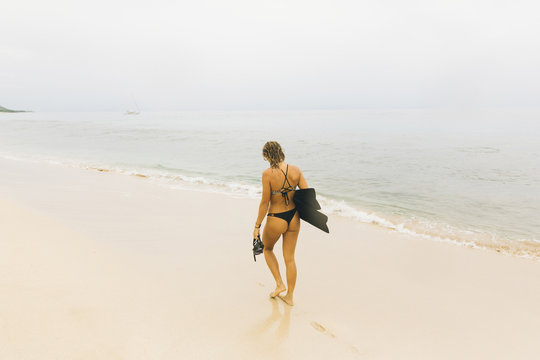 Swimmer carrying flippers, walking on beach