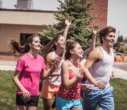 Teenage high school girls and boy running outside school