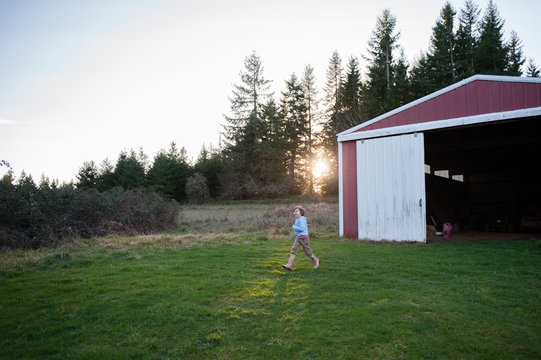 Girl walking on field by barn