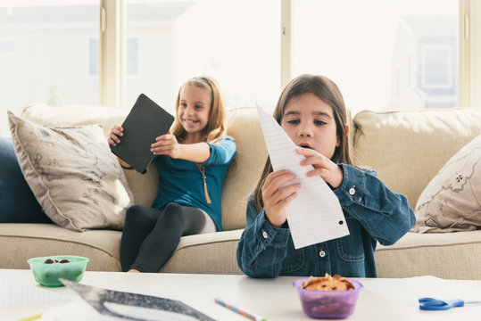 Girls at home using digital tablet, making paper airplane