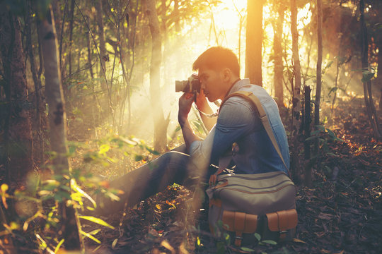 Young Man traveler with retro photo camera walking in forest Fas