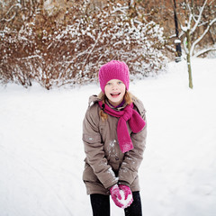 Happy Young Girl Laughing and Having Fun with Snowballs in Winte