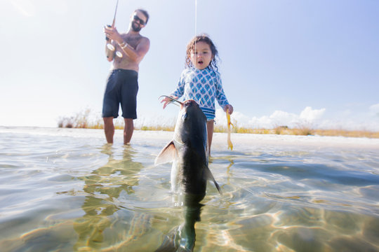 Daughter watching father catch fish in sea, Fort Walton Beach, Florida, USA