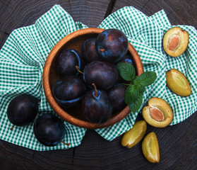 Bowl with  plums with green leaves