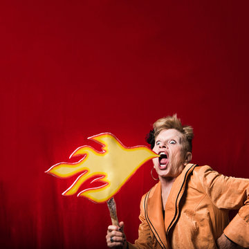 Woman holding cardboard cut-out of flames pretending to breathe fire