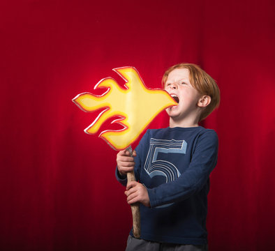 Boy holding cardboard cut-out of flames pretending to breathe fire