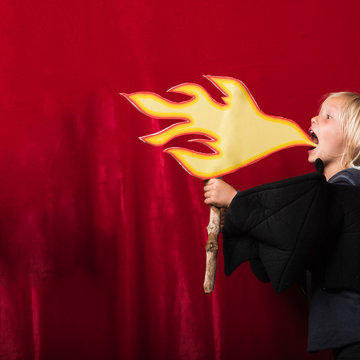 Boy holding cardboard cut-out of flames pretending to breathe fire