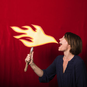 Woman holding cardboard cut-out of flames pretending to breathe fire