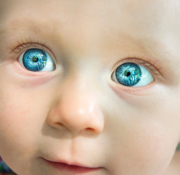 Cropped portrait of blue eyed baby girl looking away