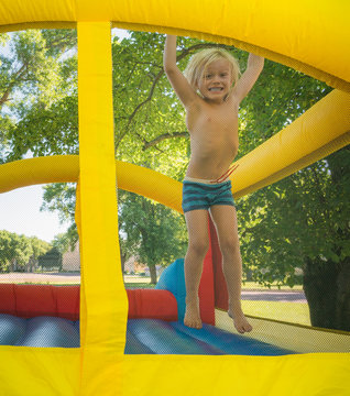 Boy jumping on bouncy castle looking at camera smiling