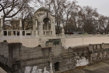 Fototapeta na wymiar Side view of Vienna Stadtpark promenade along the river, with a stone gazebo in the middle. Winter time, no people