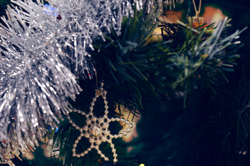 Christmas tree decorations on a tree with globes, tinsel and bells.