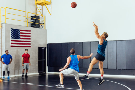 Male basketball player throwing ball toward hoop in basketball game