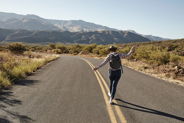 Woman walking along road markings of desert road, rear view, Sedona, Arizona, USA
