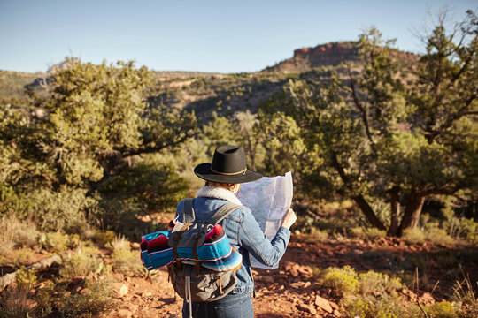 Woman in rural setting, looking at map, rear view, Sedona, Arizona, USA