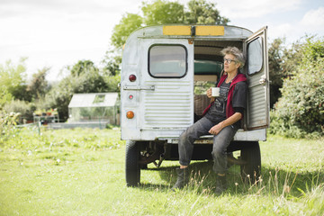 Elderly female car mechanic having a tea break