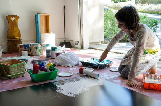 Girl in garage painting with paint roller