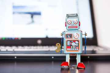 Blechroboter-Spielzeug, Methapher für Chatbot / Socialbot und Algorithmen, Laptop