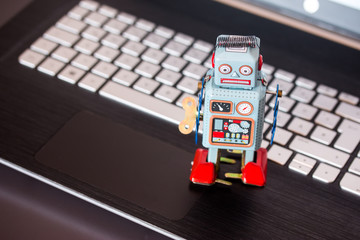 Blechroboter-Spielzeug, Methapher für Chatbot / Socialbot und Algorithmen, Laptop