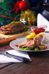 cold boiled pork on a wooden board with a glass of red wine on the background of Christmas tree
