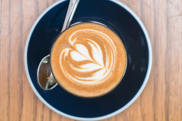 coffee cup with heart shape latte art on wood table 
