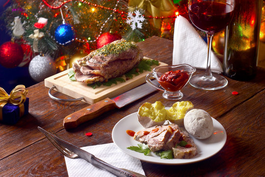 cold boiled pork on a wooden board with a glass of red wine on the background of Christmas tree