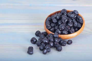 Dried blueberries fruit in wooden bowl on blue background © meteo021