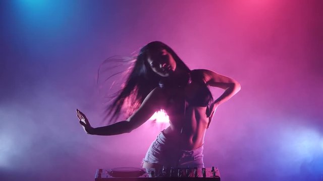 girl DJ starts dancing blue pink lights and a lot of smoke