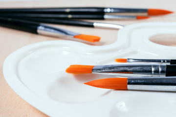 White art palette with brushes on wooden background
