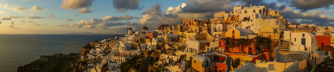 White city on a slope of a hill at sunset, Oia, Santorini, Greec