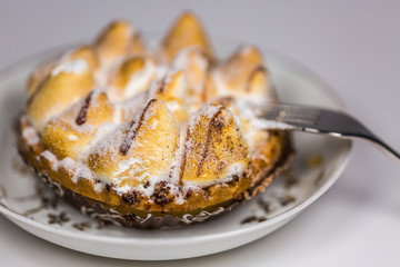 Delicious cake in white plate with fork on white table background, closeup