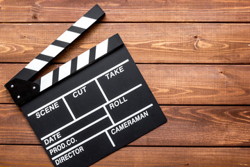 Screenwriter desktop with movie clapper board wooden background top view