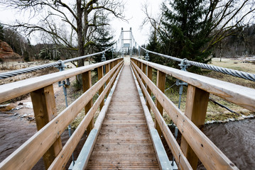 Diminishing perspective of wooden suspension footbridge over riv