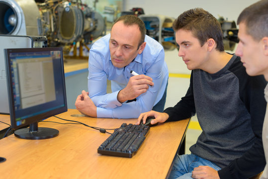Students using computer, tutor supervising