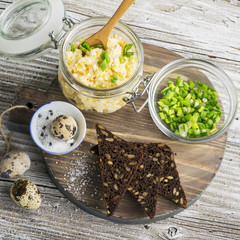 Egg salad cheese spread made toast and open sandwiches for a snack with green onions  bread roll. On  round cutting board supply. selective focus