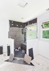 Tile installation underway in the shower area, partially covering the waterproofing board underneath