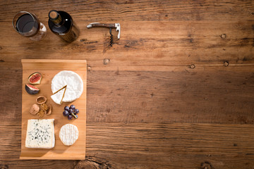 above overhead view flat lay assortment of various cheese with traditionnal bread fruits glass and bottle of red wine on old wooden table