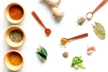 spices in wooden spoons on white background top view