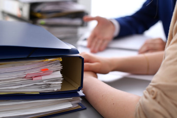 Binders with papers are waiting to be processed with businessman and secretary back in blur....