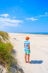 Young woman tourist standing near grass sand dune on Debki beach, Baltic Sea, Poland