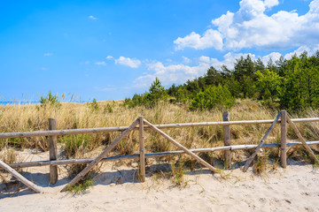 Fototapeta na wymiar Wooden fence on sand dune on coast of Baltic Sea near Lubiatowo beach, Poland