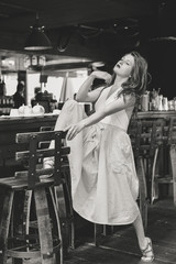 Portrait of attractive young lady in blue dress relaxing sitting in restaurant interior background.