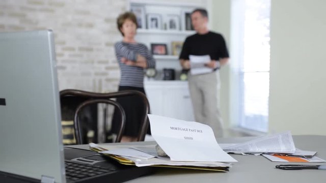 A couple quarreling about finances. Laptop main focus  people out of focus.