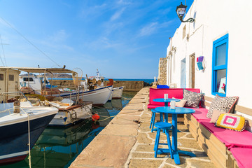 Fototapeta na wymiar Cafe bar in Naoussa port with mooring fishing boats on Paros island, Greece
