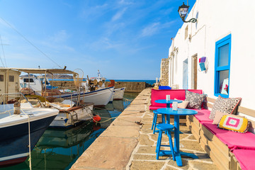 Cafe bar in Naoussa port with mooring fishing boats on Paros island, Greece