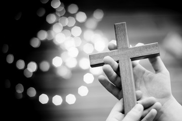 Little boy child praying and holding wooden crucifix