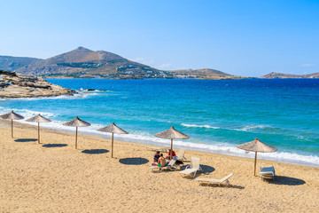 Sun umbrellas on sandy beach in Naoussa town, Paros island, Greece