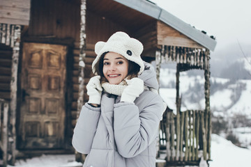 girl in a funny hat on the background of wooden house