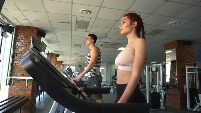 Fitness man and woman walking on treadmill